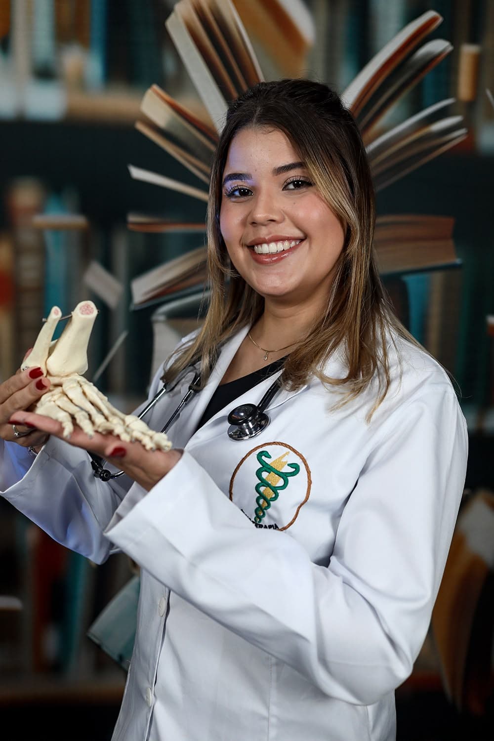 Vitória sorrindo e segurando um modelo anatômico do pé