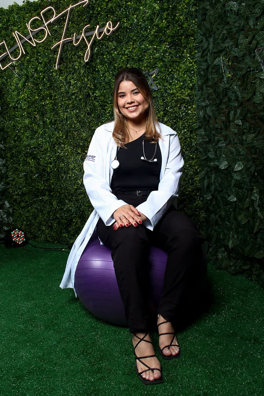 Vitória sorrindo, sentada em uma bola suíça de fisioterapia