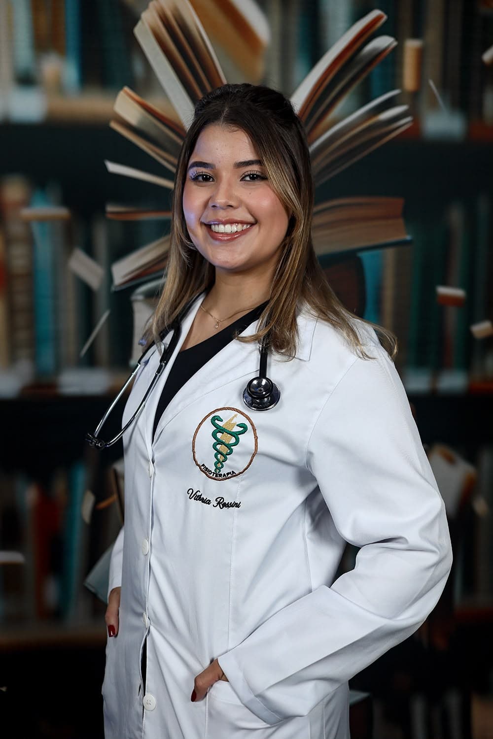 Vitória Rossini sorrindo, de jaleco com o bordado da Fisioterapia e estetoscópio