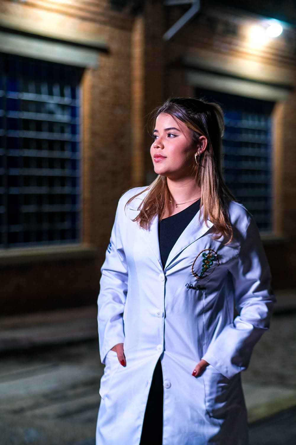 Vitória de jaleco olhando para o horizonte, à noite